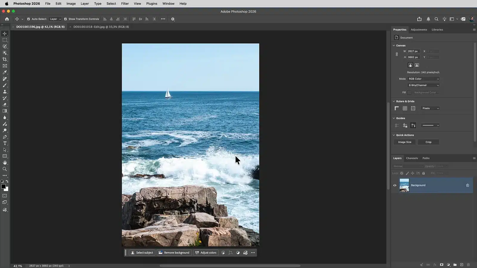 Staande foto van een zeilboot aan de horizon met rotsen en golven op de voorgrond in Photoshop