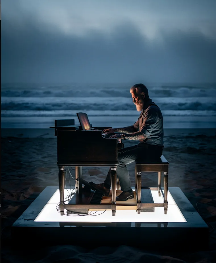 Dezelfde muzikant en hetzelfde podium, nu op een strand op het blauwe uur